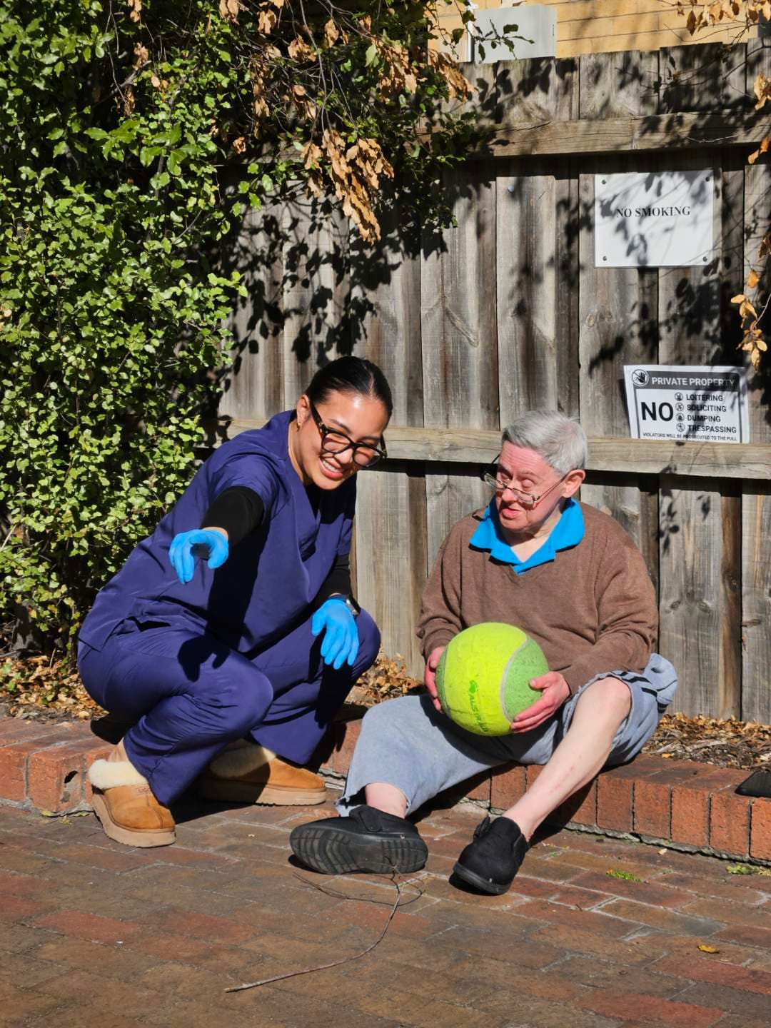 Carer and resident playing with a ball in the courtyard