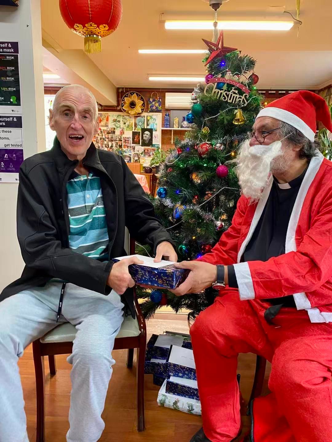 Santa Claus handing a Christmas gift to a resident